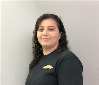 Headshot of half-smiling woman wearing a black SERVPRO t-shirt in front of a gray background