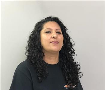 Headshot of half-smiling woman wearing a black SERVPRO t-shirt in front of a gray background