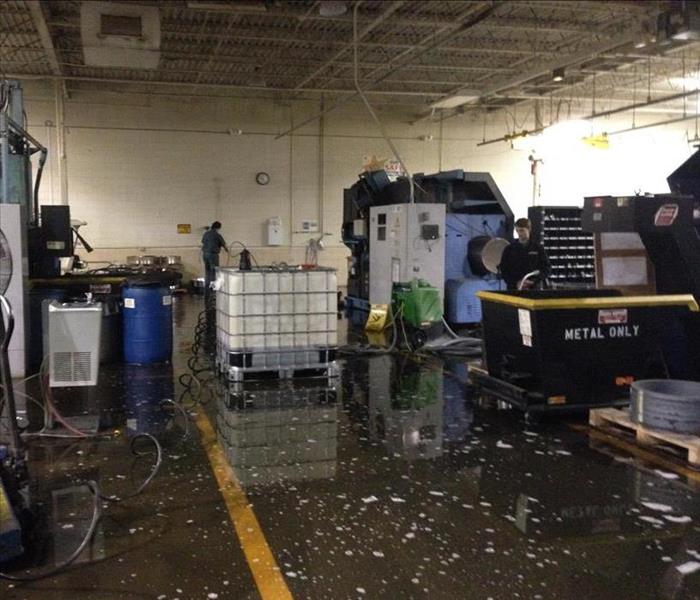 Water covering the concrete floor of a warehouse full of equipment