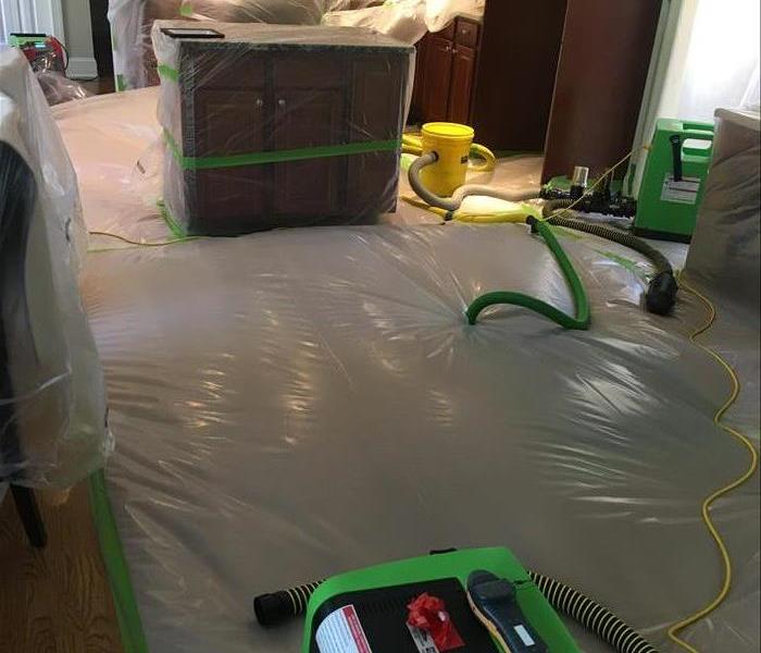 Pipes and green equipment enter a plastic cover on top of hardwood floor