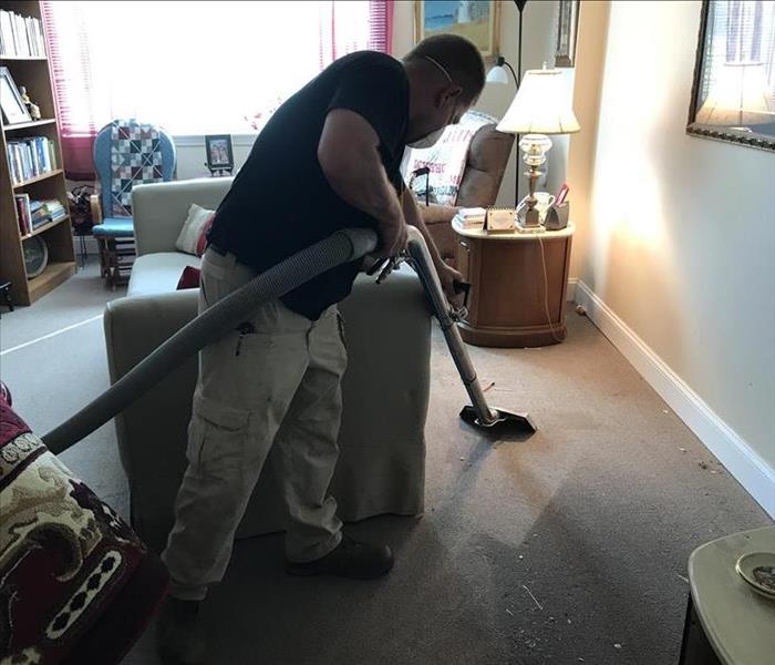 SERVPRO employee sucking up water from carpet with vacuum-like machine