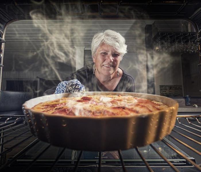 Old woman puts a pie into an oven